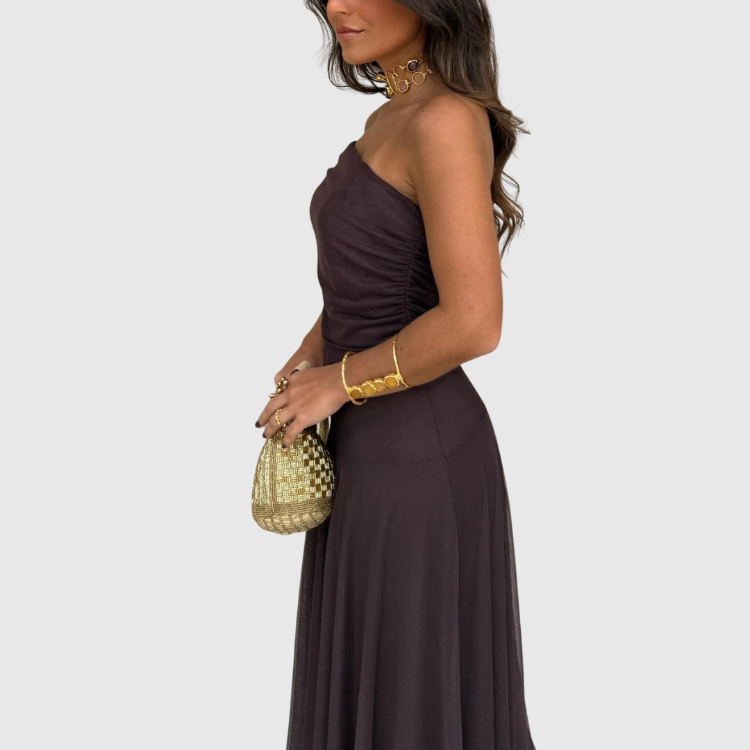 Woman in strapless brown maxi dress holding gold textured bag – Frau im trägerlosen braunen Maxikleid mit goldener Tasche.