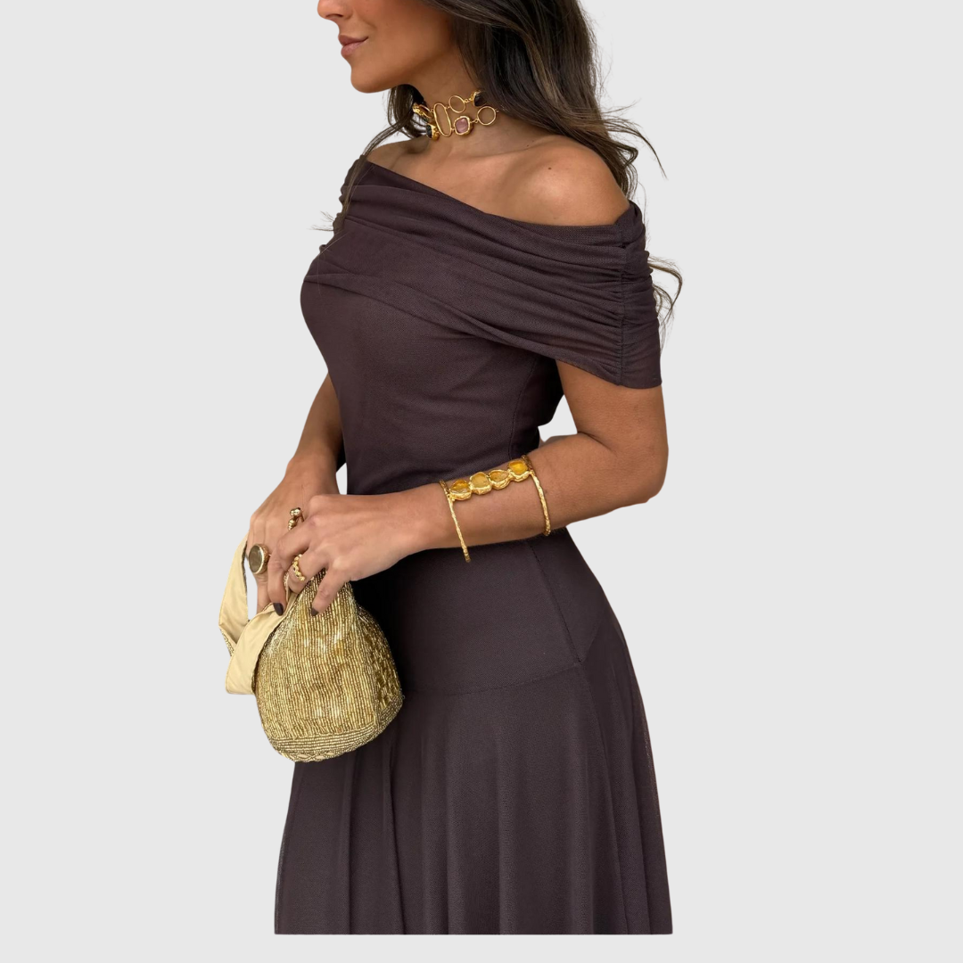 Primo piano laterale di una donna in un elegante abito marrone con una borsa decorata in oro.